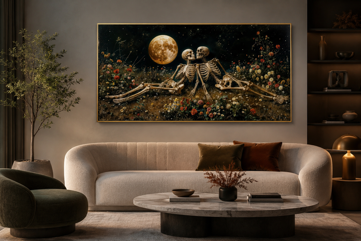 Romantic gothic wall art of two skeletons in a floral meadow under a full moon above a sofa.