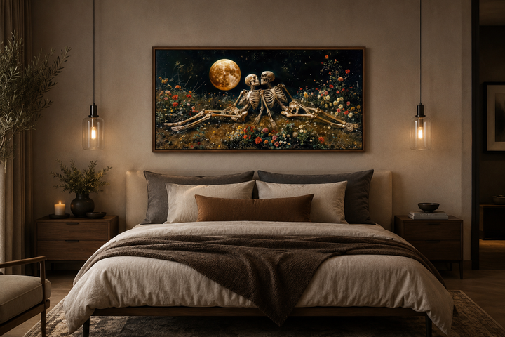 Framed wall art of two skeletons in a flower meadow under a full moon above a bed.