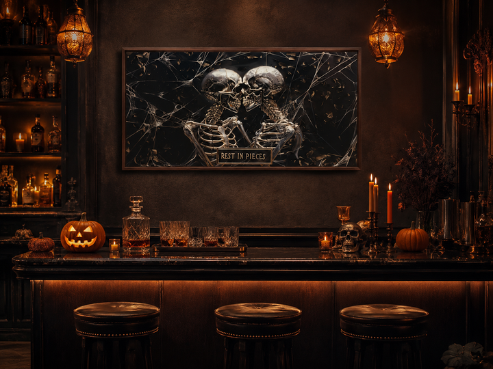 Framed gothic wall art of two skeletons with a "Rest In Pieces" plaque above a Halloween bar setup.
