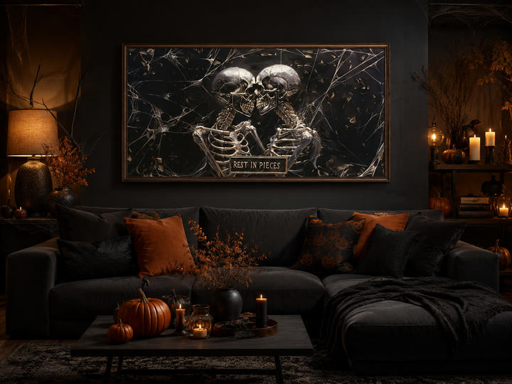 Framed gothic painting of two skeletons with a "Rest In Pieces" plaque in a dark living room.