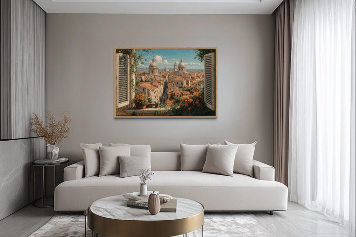 A framed canvas print of a sunlit Rome skyline viewed through an open window above a modern sofa.