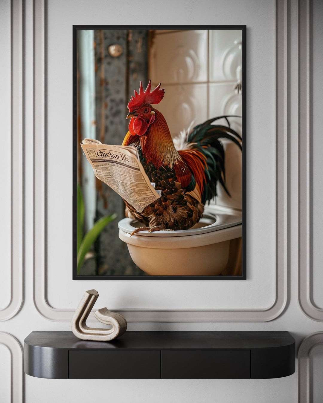 Framed canvas of a rooster sitting on a toilet reading a newspaper, mounted on a paneled wall.