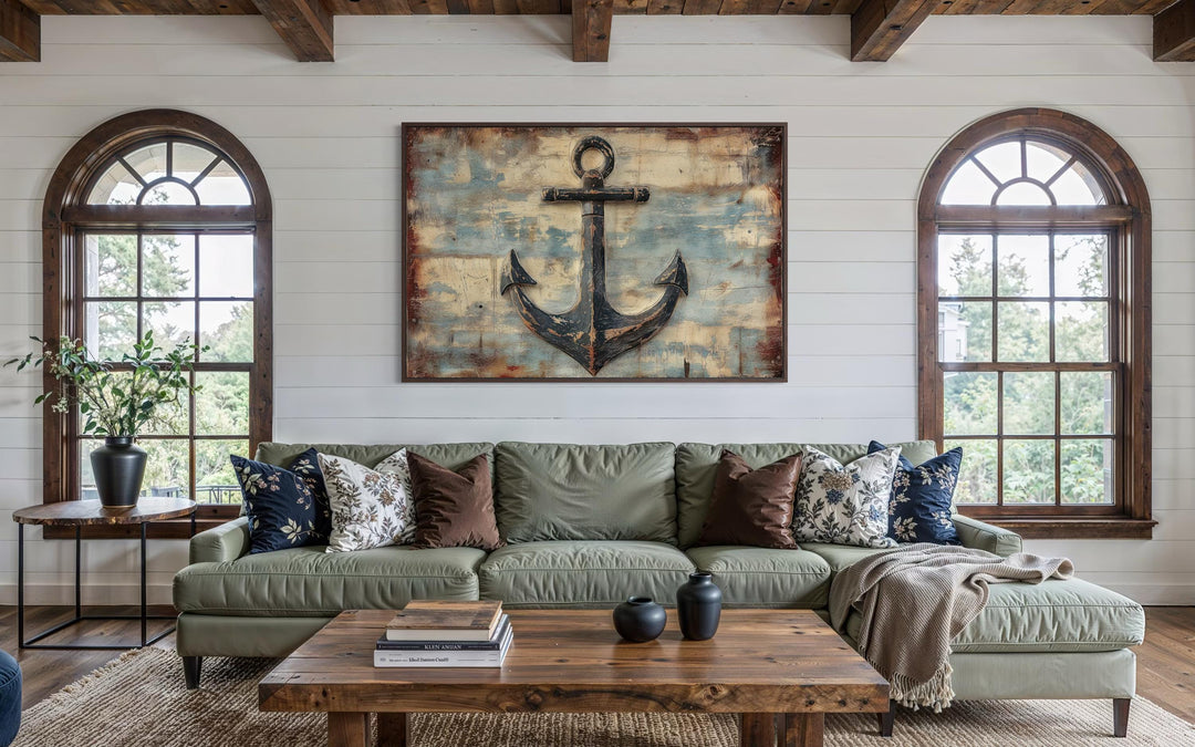 Rustic anchor wall art on a weathered wood-style canvas hangs above a green sofa in a coastal room.
