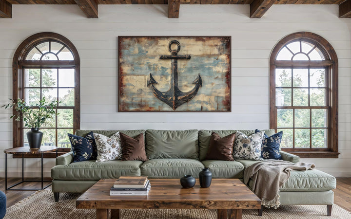 Rustic anchor wall art on a weathered wood-style canvas hangs above a green sofa in a coastal room.
