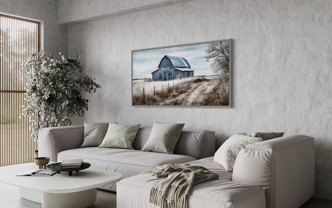 Rustic blue barn canvas painting hanging above a neutral sofa in a farmhouse-style living room.