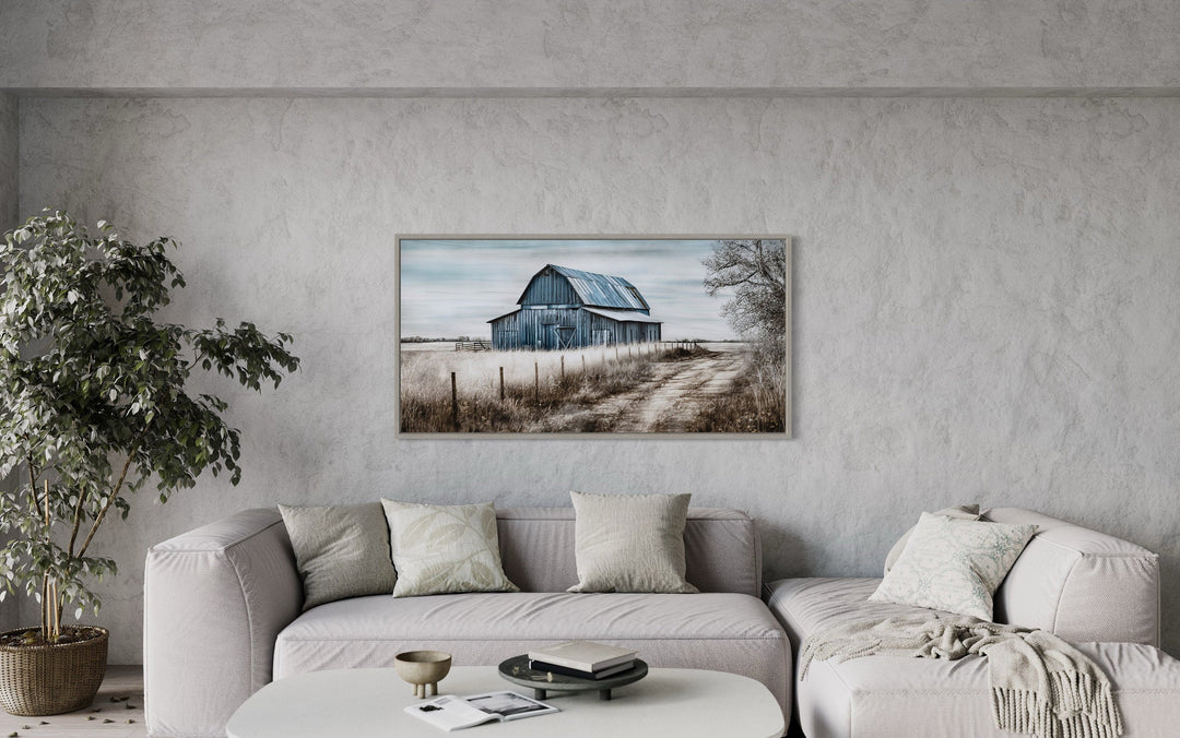 Rustic blue barn canvas painting hanging above a neutral sofa in a farmhouse-style living room.