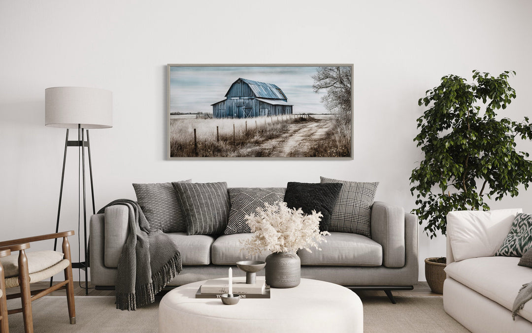 Rustic blue barn canvas painting hanging above a gray sofa in a farmhouse-style living room.