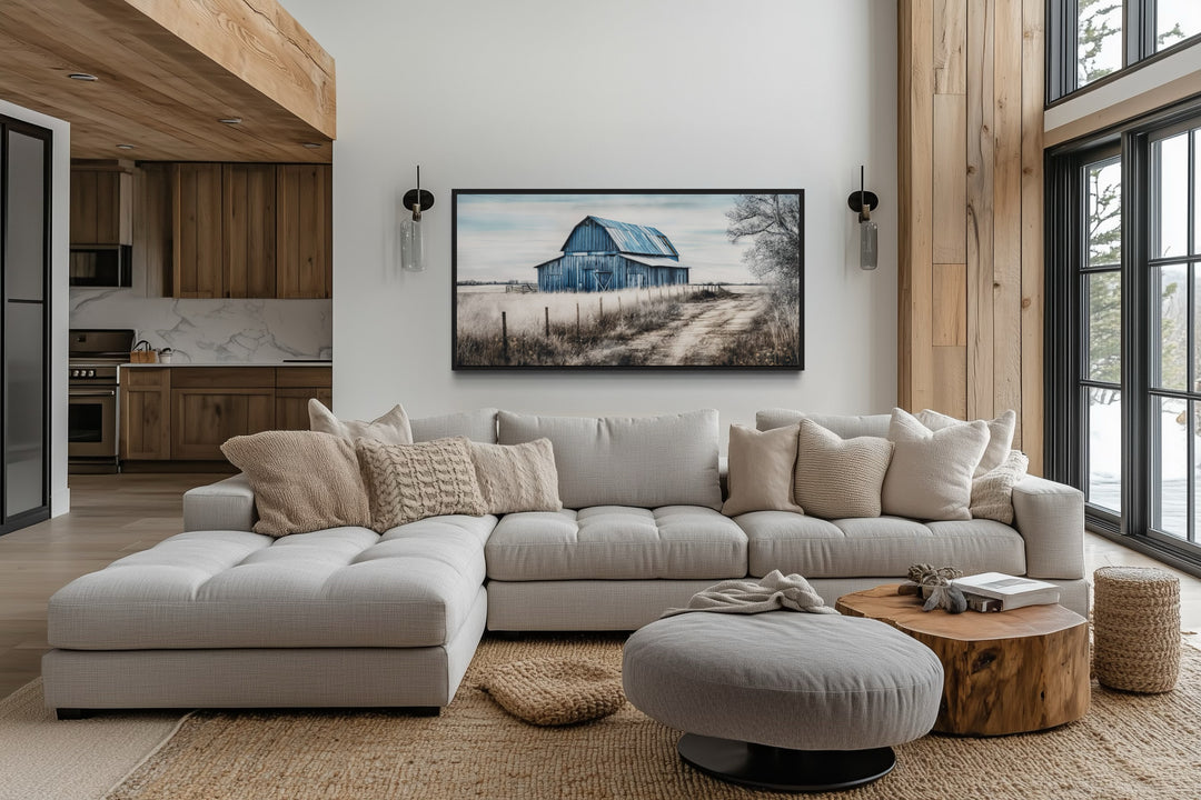 Rustic blue barn canvas painting hanging above a light gray sectional sofa in a farmhouse living room