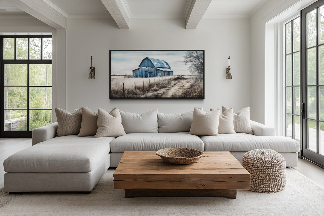 Rustic blue barn canvas painting centered above a modern sofa in a farmhouse living room.