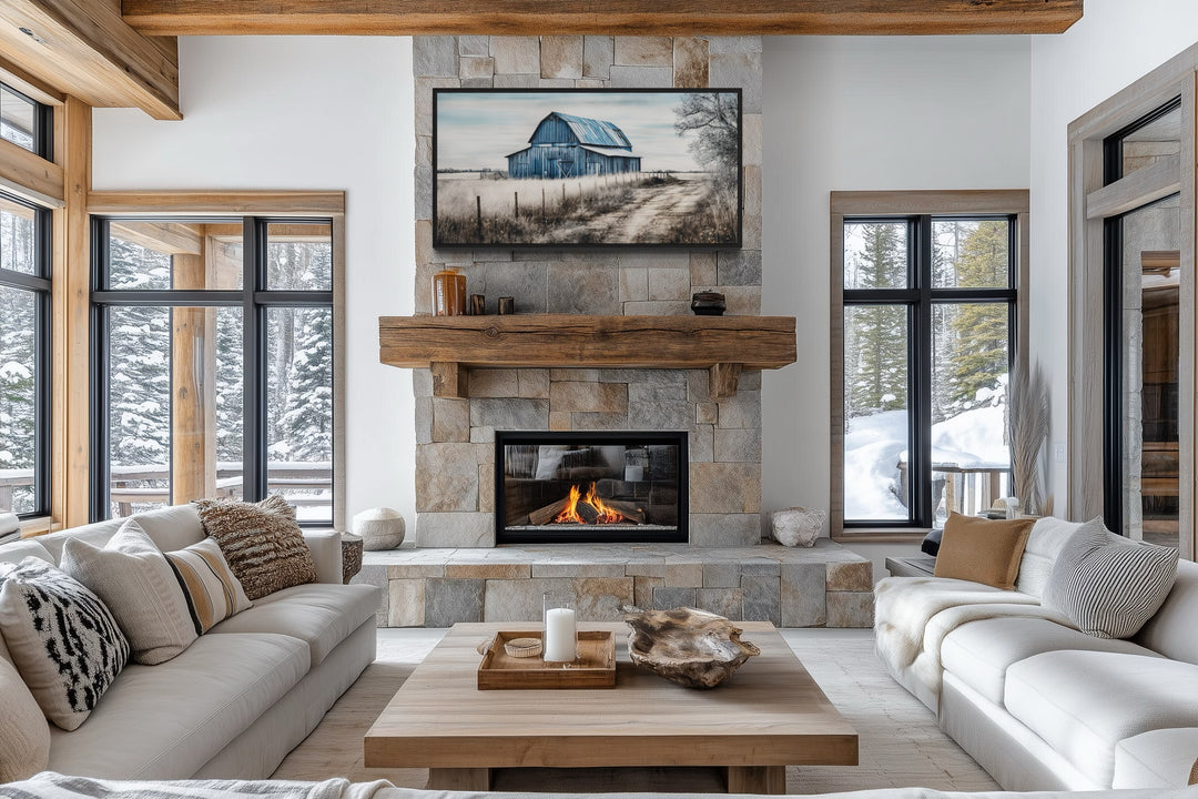 Rustic blue barn canvas painting mounted above a stone fireplace in a farmhouse living room.