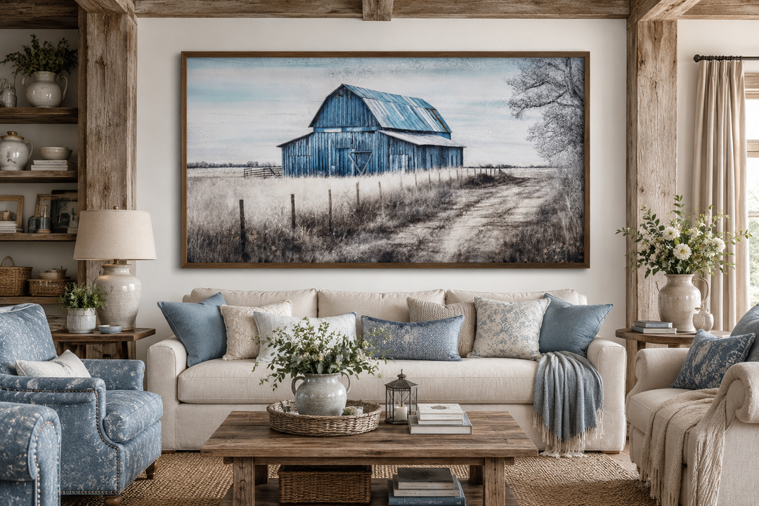 Rustic blue barn canvas painting in a wooden frame above a farmhouse sofa in a cozy living room.