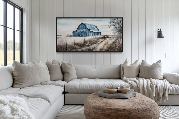 Rustic blue barn canvas painting hanging above a neutral sectional sofa in a farmhouse living room.
