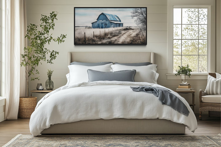 Rustic blue barn canvas painting hanging above a bed in a farmhouse-style bedroom.