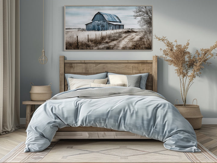 Rustic blue barn canvas painting hanging above a wooden bed in a farmhouse-style bedroom.