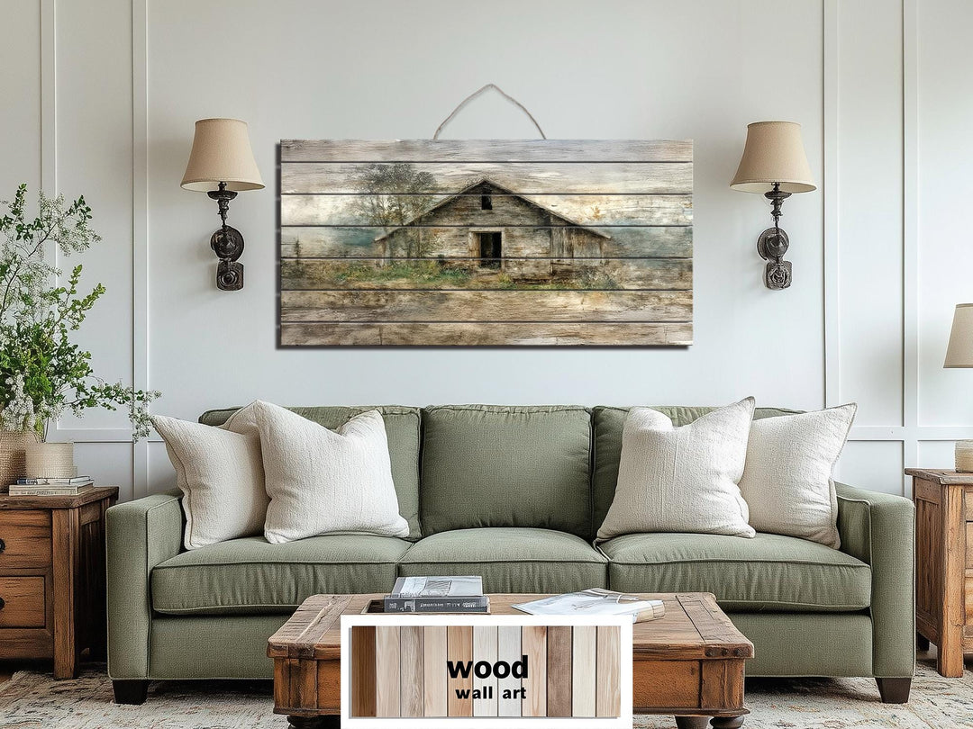 Rustic barn landscape printed on a horizontal distressed wood panel above a green sofa.