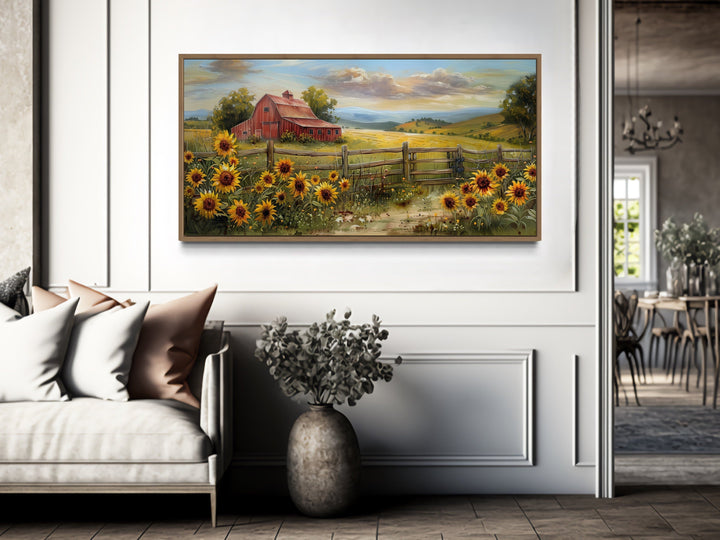 Panoramic rustic red barn and sunflower canvas print hanging on a white wall above a sofa.