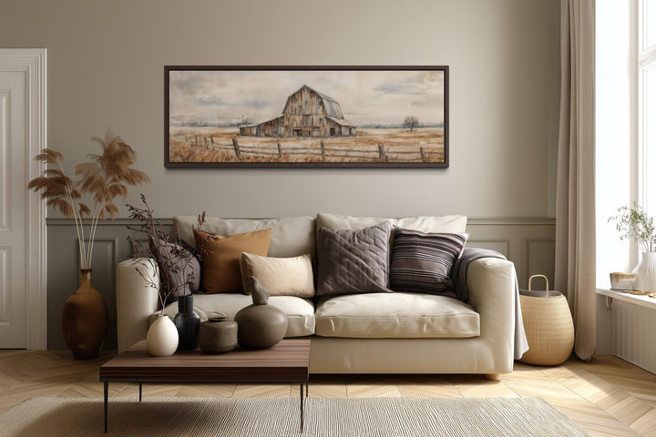 A long horizontal canvas print of a rustic barn hangs above a neutral sofa in a farmhouse living room.
