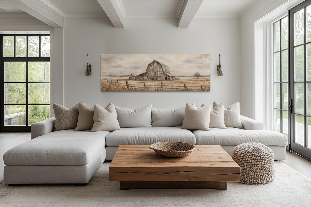 A long horizontal canvas print of a rustic barn hangs above a neutral sofa in a farmhouse living room.