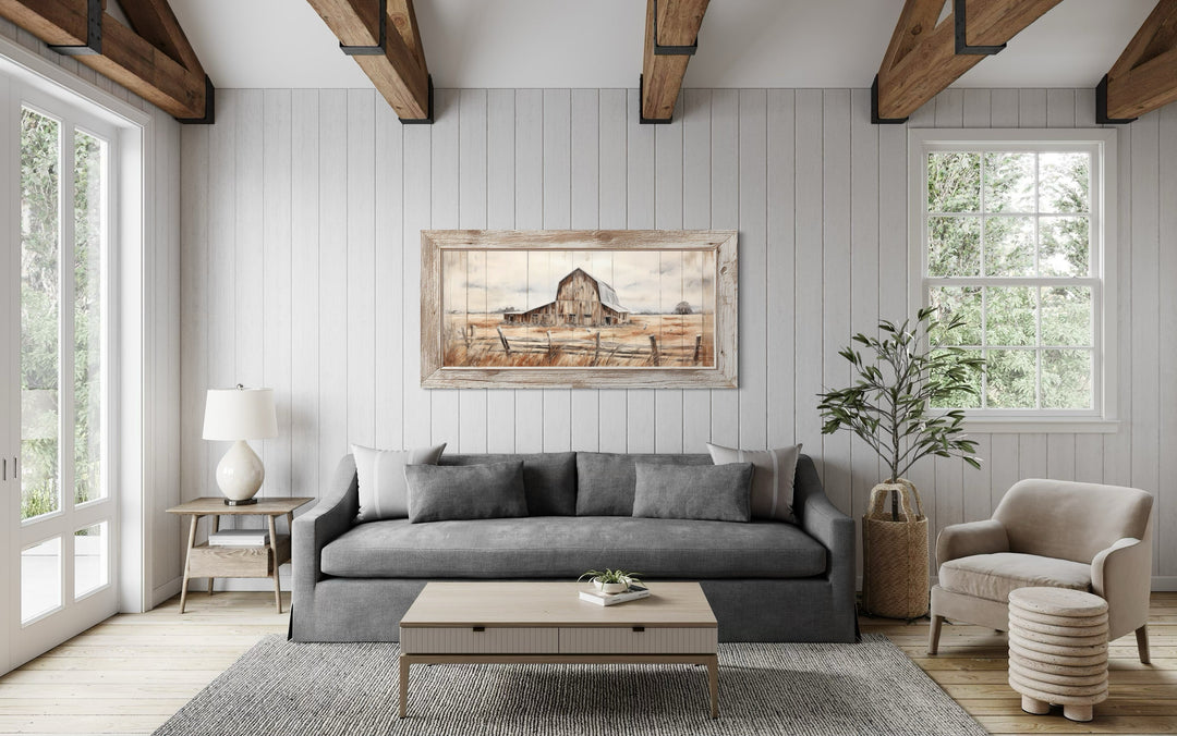 Rustic barn wall art in a weathered frame hanging above a gray sofa in a farmhouse living room.