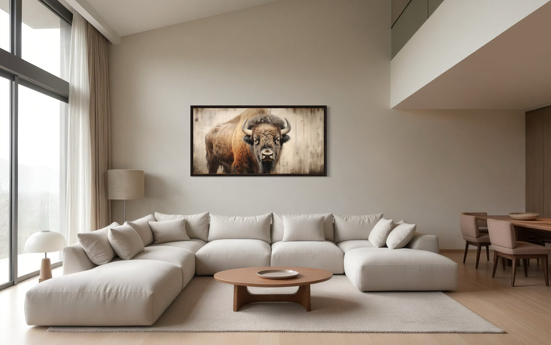 Rustic bison framed canvas print on a neutral wall above a modern sectional sofa in a living room.