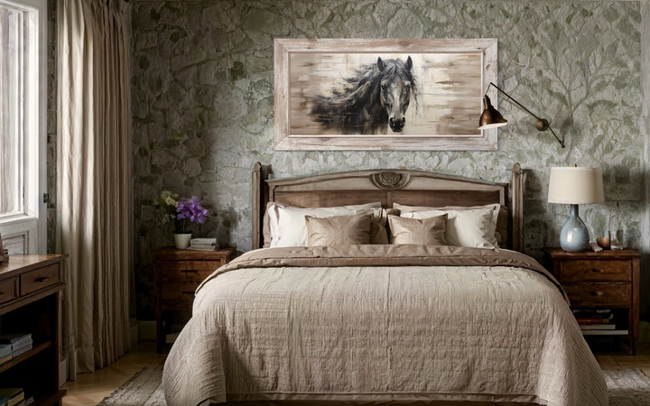 Rustic black horse painting on wood-effect canvas in a light wood frame above a farmhouse bed.