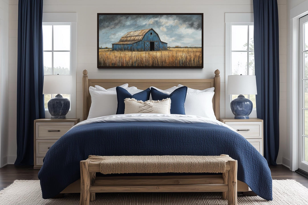 Rustic blue barn framed canvas wall art hanging above a bed in a farmhouse style bedroom.