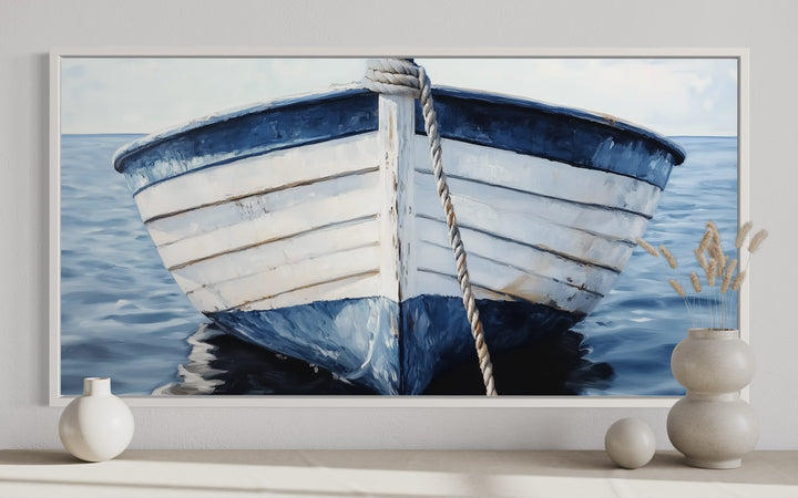 Rustic blue and white boat canvas wall art in a white frame above a shelf with decorative vases.