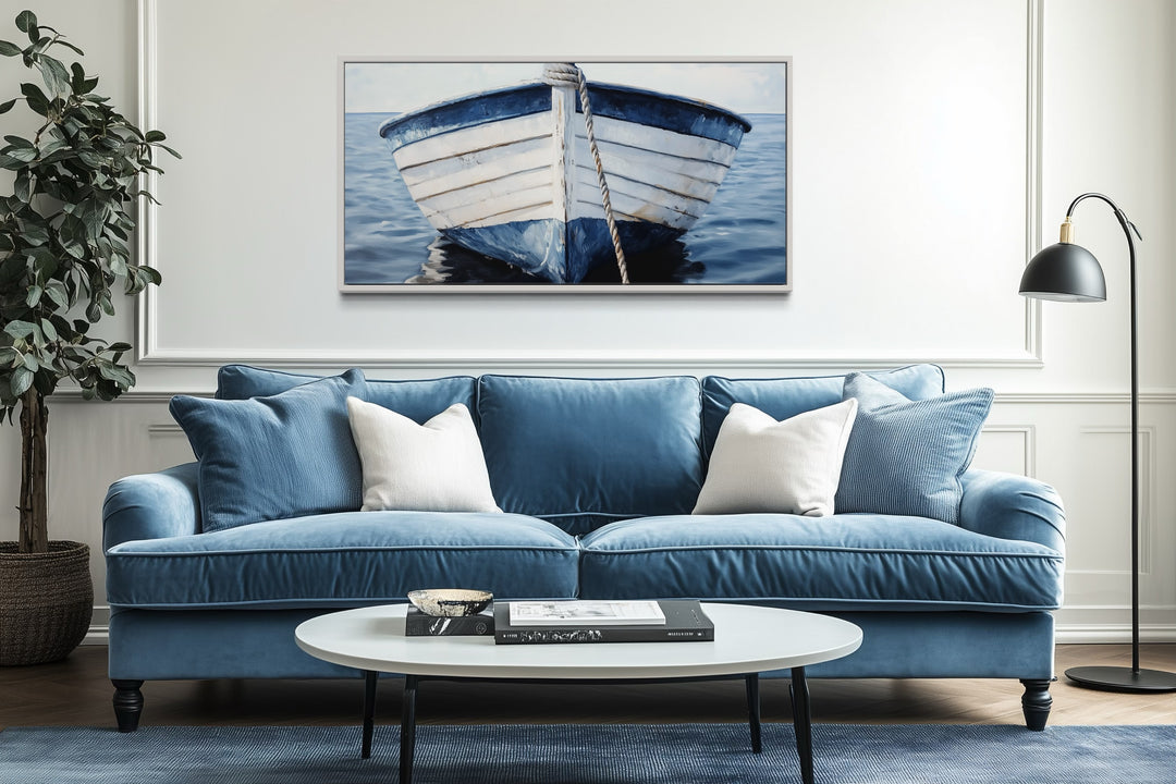 Rustic blue and white boat canvas wall art hanging above a blue sofa in a coastal living room.