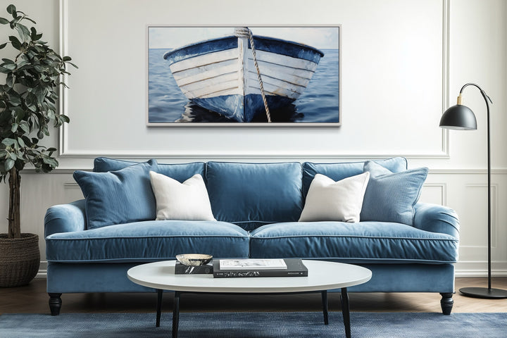 Rustic blue and white boat canvas wall art hanging above a blue sofa in a coastal living room.