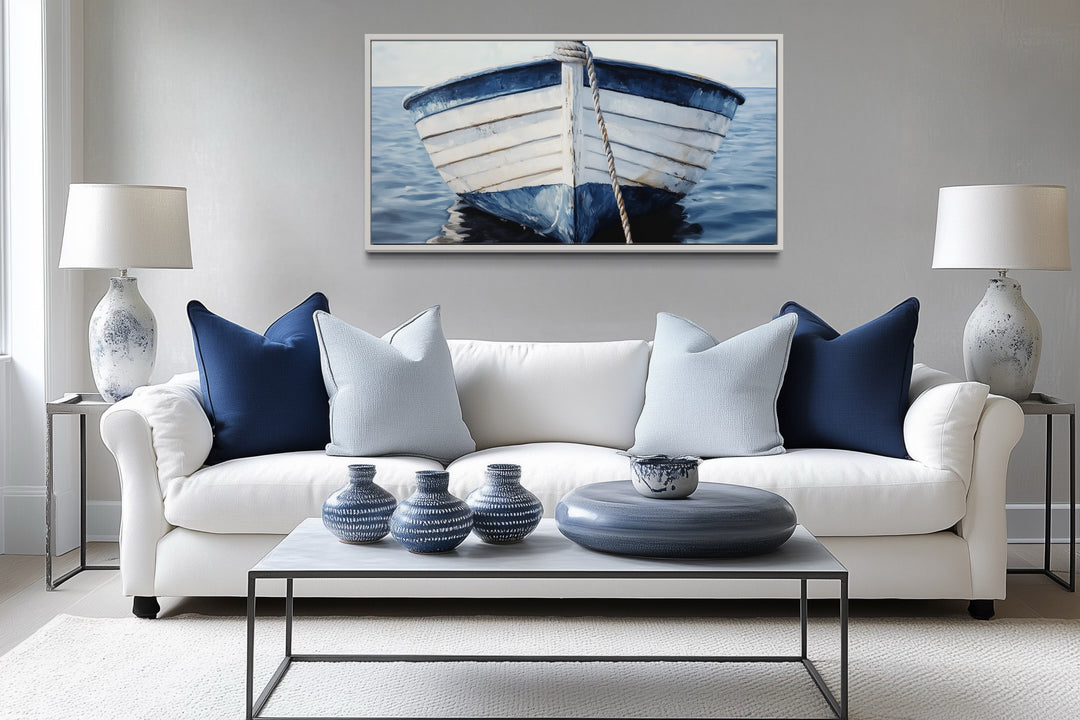 Rustic boat wall art in blue and white, framed above a white sofa with coastal nautical decor.