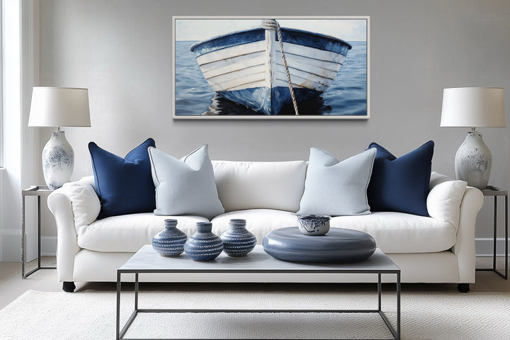 Rustic boat wall art in blue and white, framed above a white sofa with coastal nautical decor.