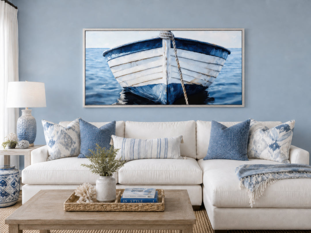 Rustic blue and white boat wall art framed above a white sectional sofa in a coastal living room.
