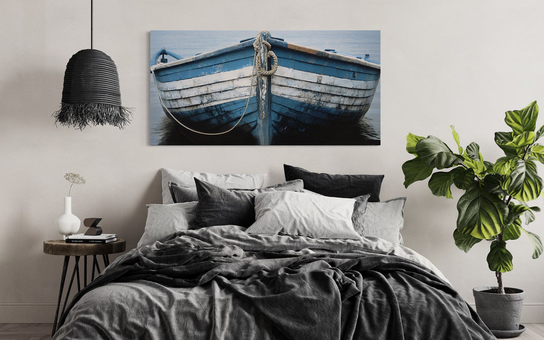 Rustic blue and white boat canvas print hanging above a bed in a coastal-themed bedroom.