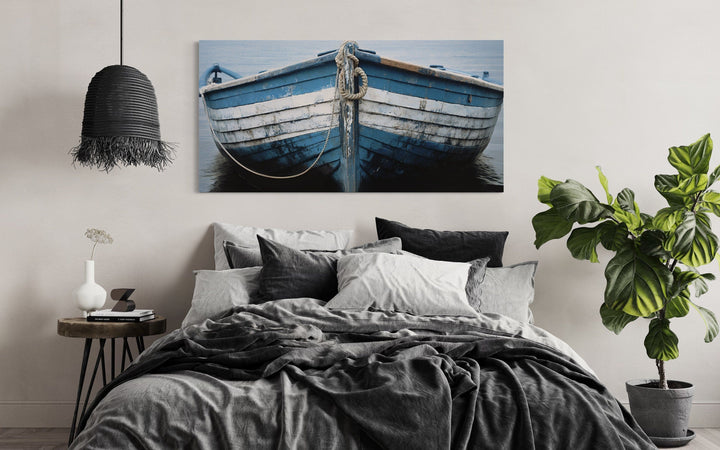 Rustic blue and white boat canvas print hanging above a bed in a coastal-themed bedroom.