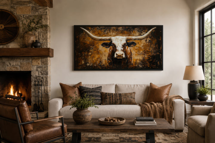 A large horizontal canvas painting of a longhorn bull hangs above a sofa in a rustic living room.