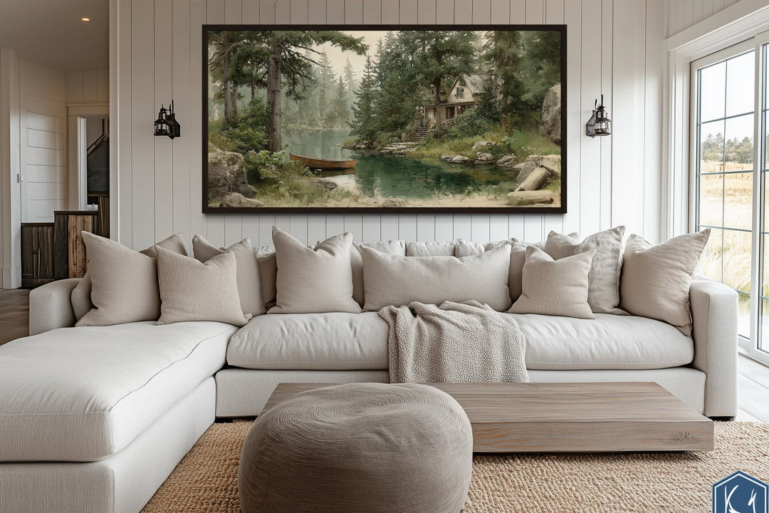 Framed rustic cabin wall art featuring a wooden boat on a serene lake above a modern white sofa.