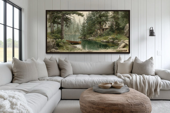 Panoramic framed painting of a wooden boat on a serene lake by a rustic cabin in a forest.
