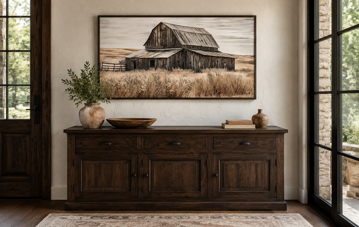 Rustic chic old farm barn painting on wood framed canvas wall art above a dark wood sideboard.