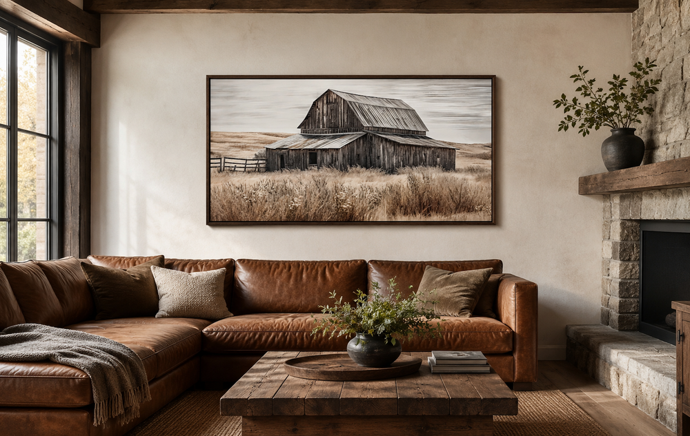 Rustic chic old farm barn painting on wood framed canvas wall art above a brown leather sofa.
