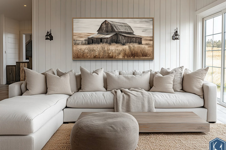Rustic old farm barn painting on wood framed canvas wall art above a neutral sectional sofa.