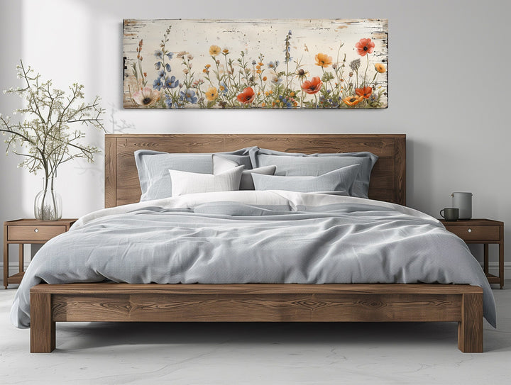 Rustic chic long narrow wall art featuring colorful wildflowers over a wooden bed frame.