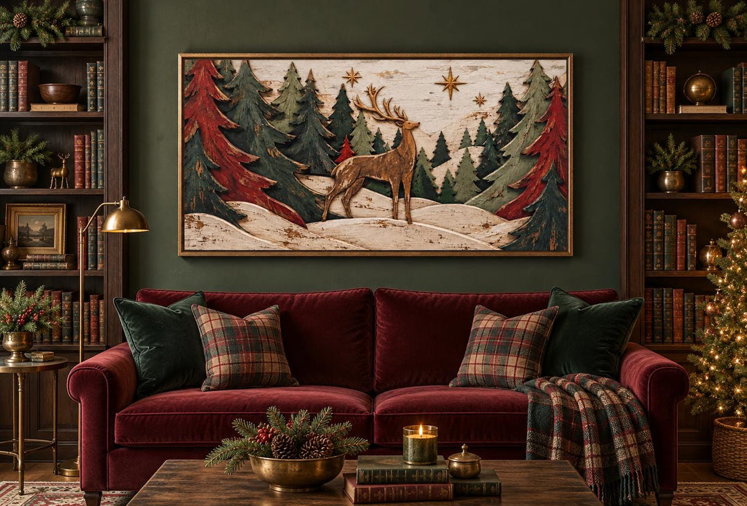 Rustic Christmas deer with red and green trees framed canvas wall art above a red velvet sofa.