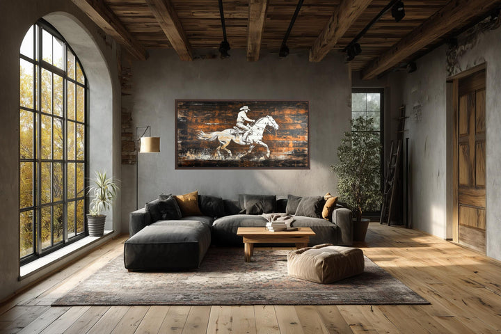 Rustic cowboy on horse canvas wall art on dark wood planks in a modern industrial living room.