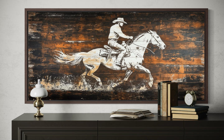Rustic cowboy on horse wall art featuring a white sketch on dark wood planks in a brown frame.