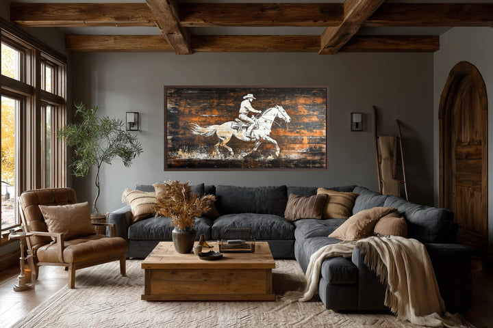 Rustic cowboy on horse wall art on dark wood planks in a cozy, modern farmhouse living room.
