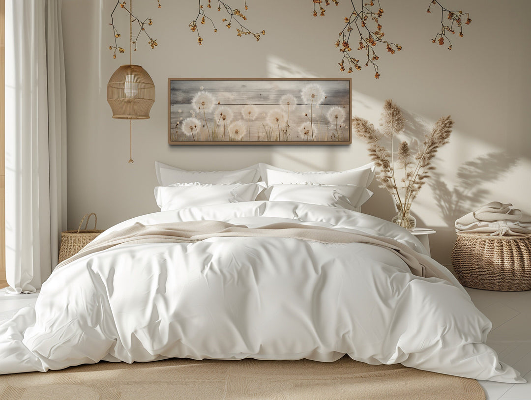 Rustic horizontal painting of dandelions on wood, framed and hanging above a bed in a bedroom.