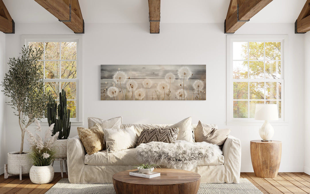 Rustic horizontal wall art featuring dandelions painted on a wood-textured background above a sofa.