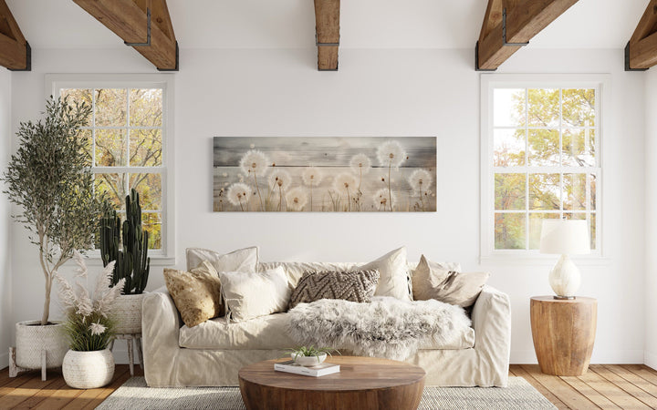 Rustic horizontal wall art featuring dandelions painted on a wood-textured background above a sofa.