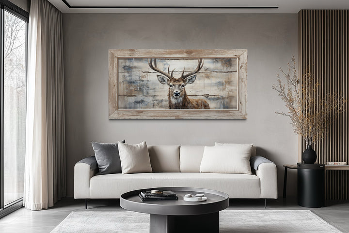Rustic deer painting on wood canvas wall art in a wooden frame above a modern sofa in a living room.