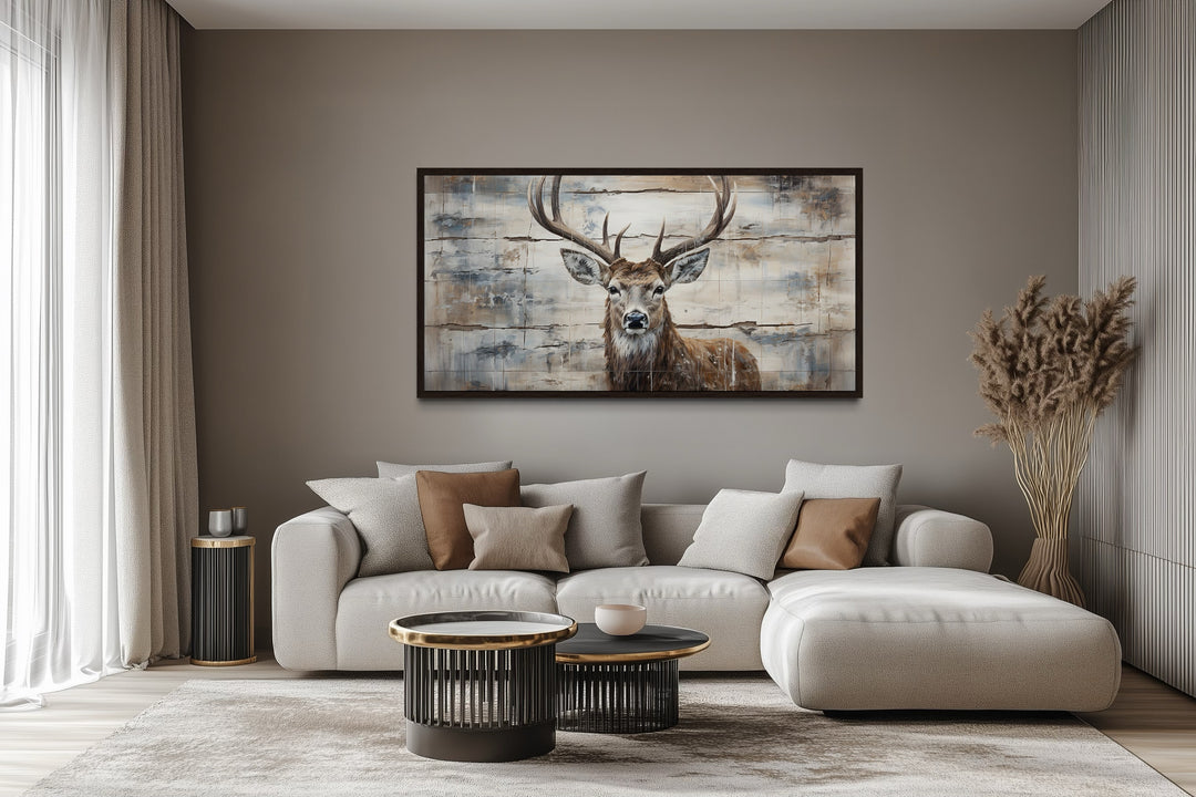 Rustic deer painting on wood canvas wall art hanging above a modern sofa in a cabin-style room.